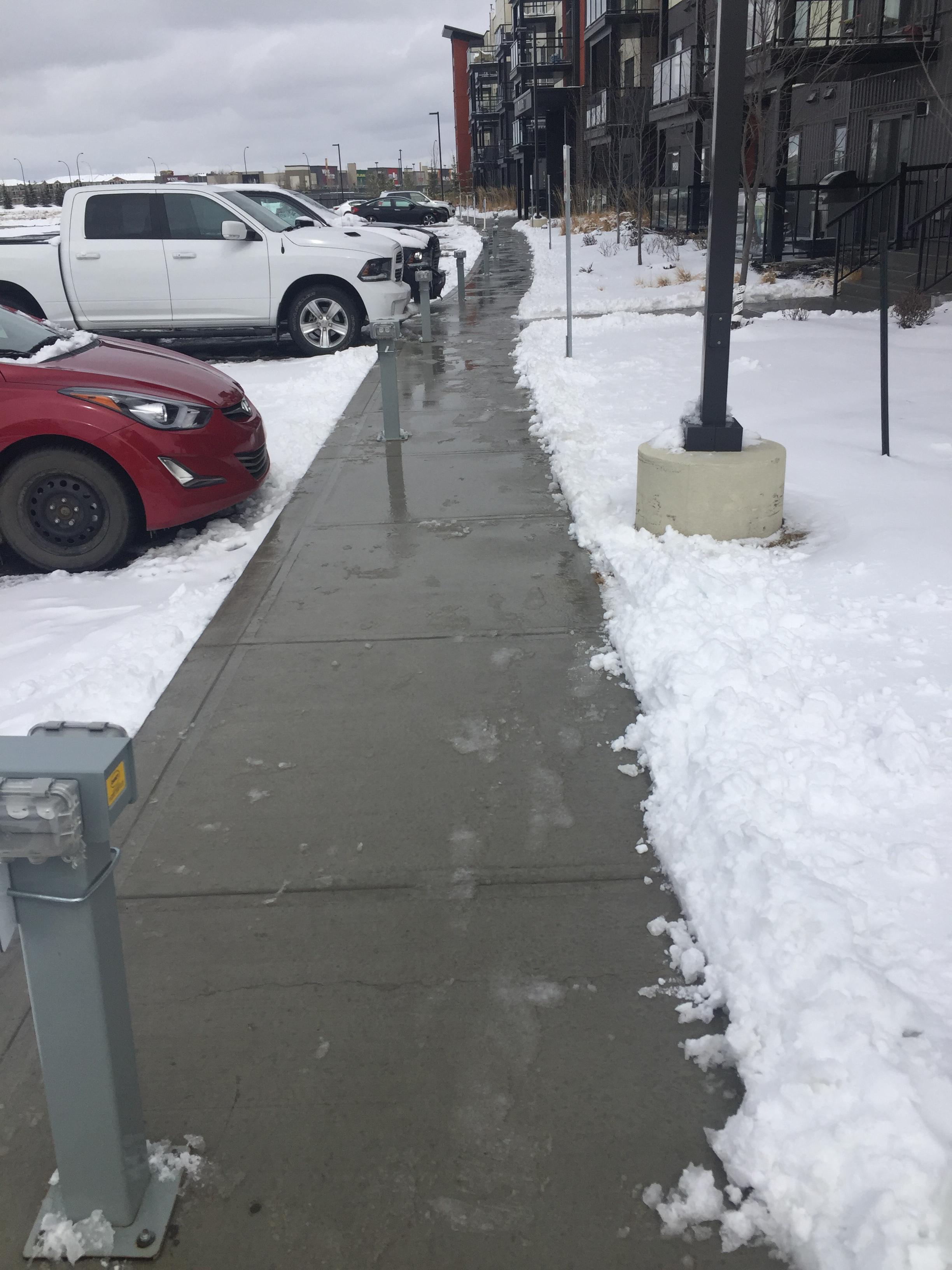 Commercial sidewalk cleared with snow banks on either side